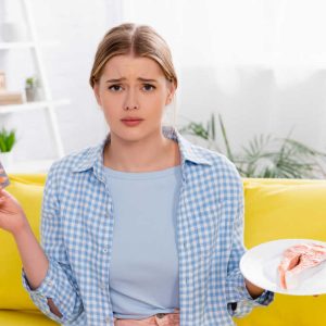 Sad woman with allergy holding pills and salmon